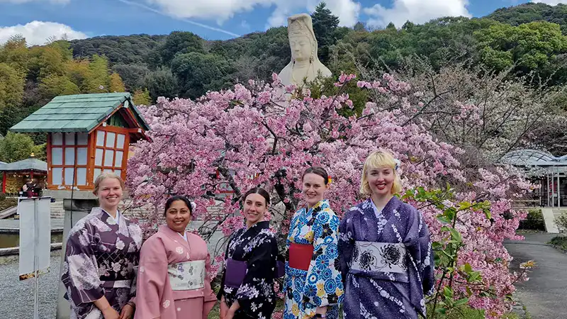Female travellers in front of the temple experiencing Sakura blooms