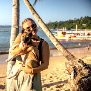 Tour guide hugs local puppy in Port Barton while on tour