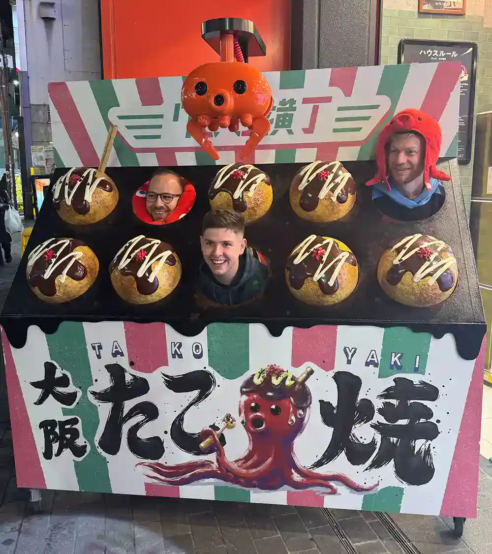 Friends enjoy kirky Japanese Takoyaki photobooth in streets of Osaka