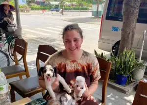 Woman at roadside cafe in Vietnam with puppy and kitten