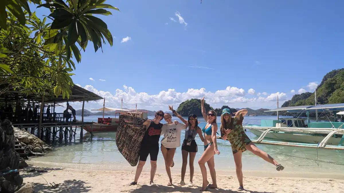 Group of friends on a white sand beach while island hopping in Coron, Palawan