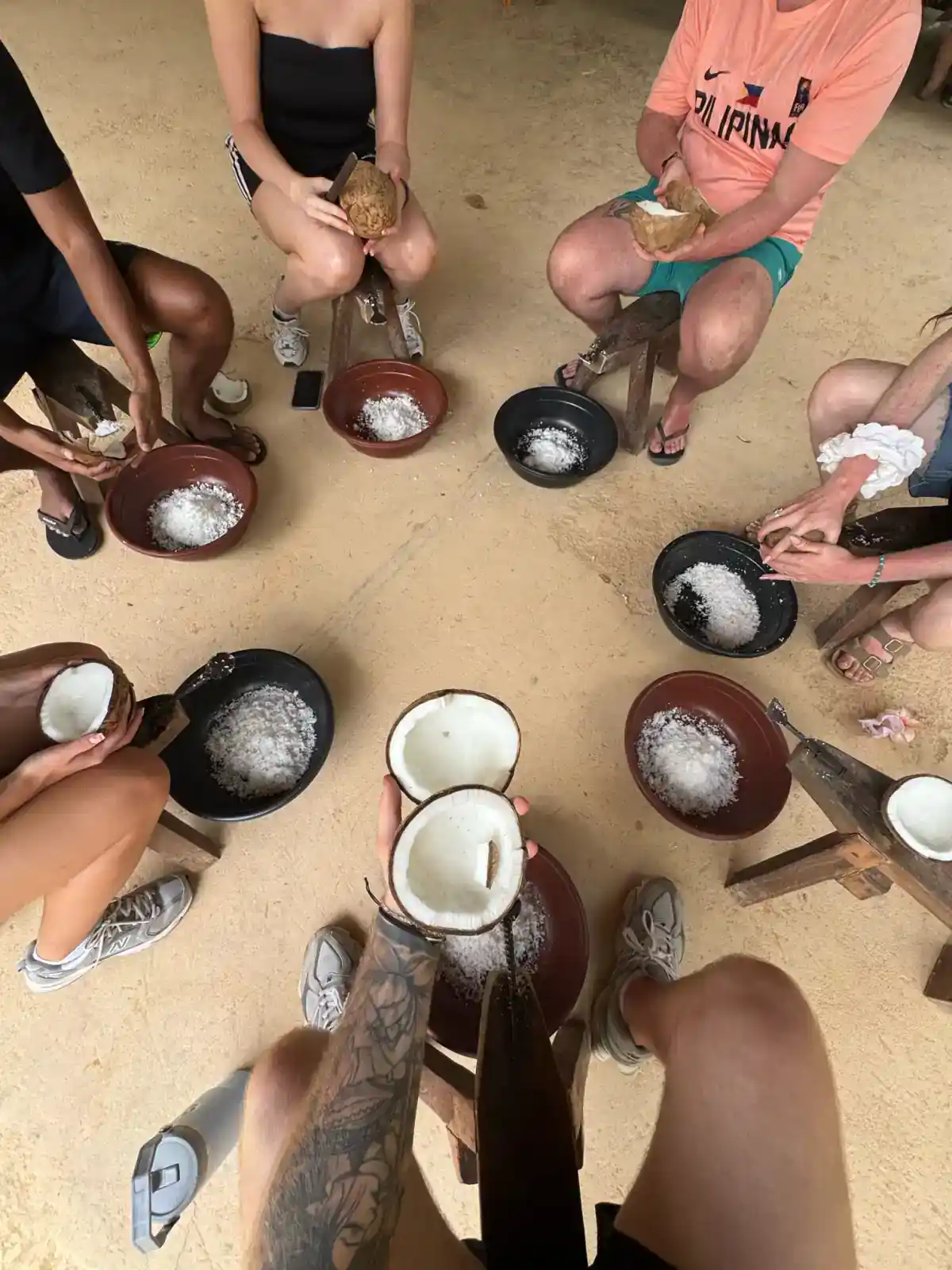 Travellers shaving coconuts together during a Filipino cultural day in El Nido