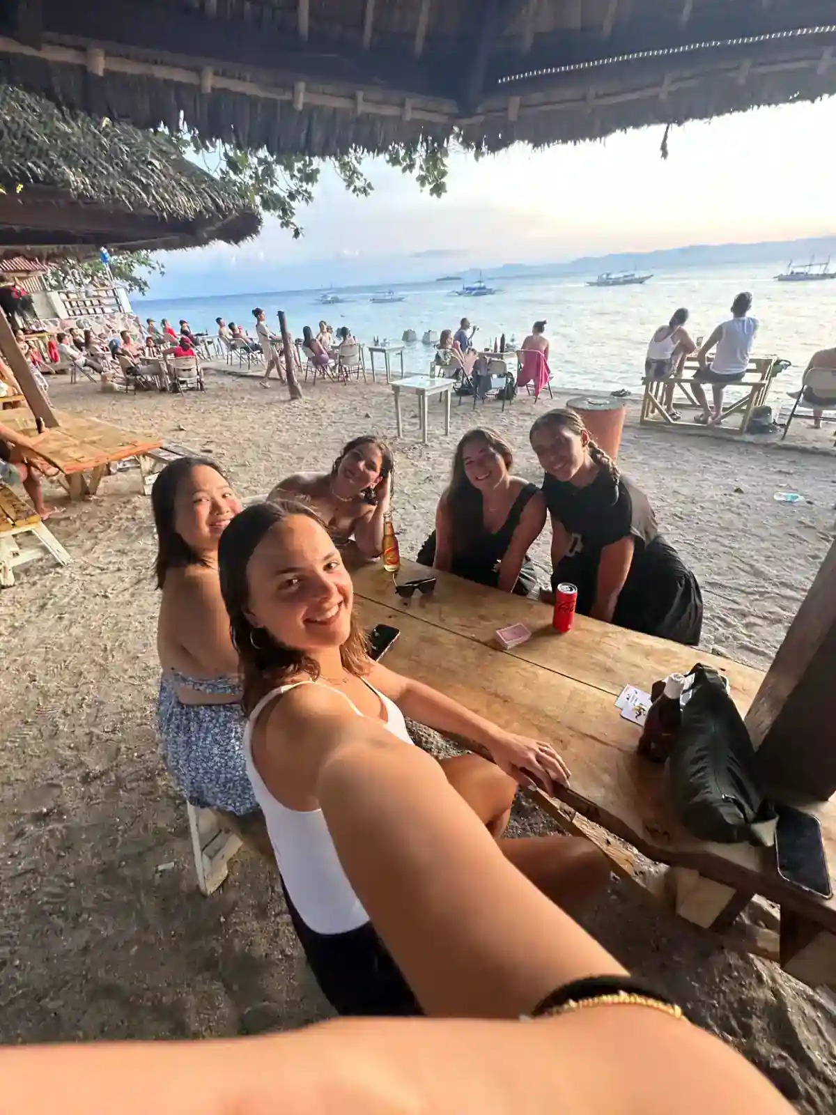New friends from a Philippines group tour sharing drinks at a beach bar at sunset